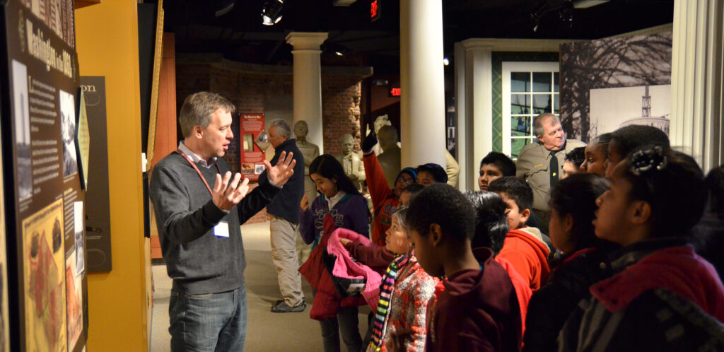 A class of elementary school students listen to a Ford’s Education staff guide while looking at images of Washington during the Civil War in the museum.