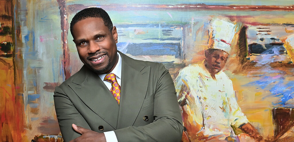 Headshot of Nolan Williams, Jr. standing in front of a painted mural of a chef.