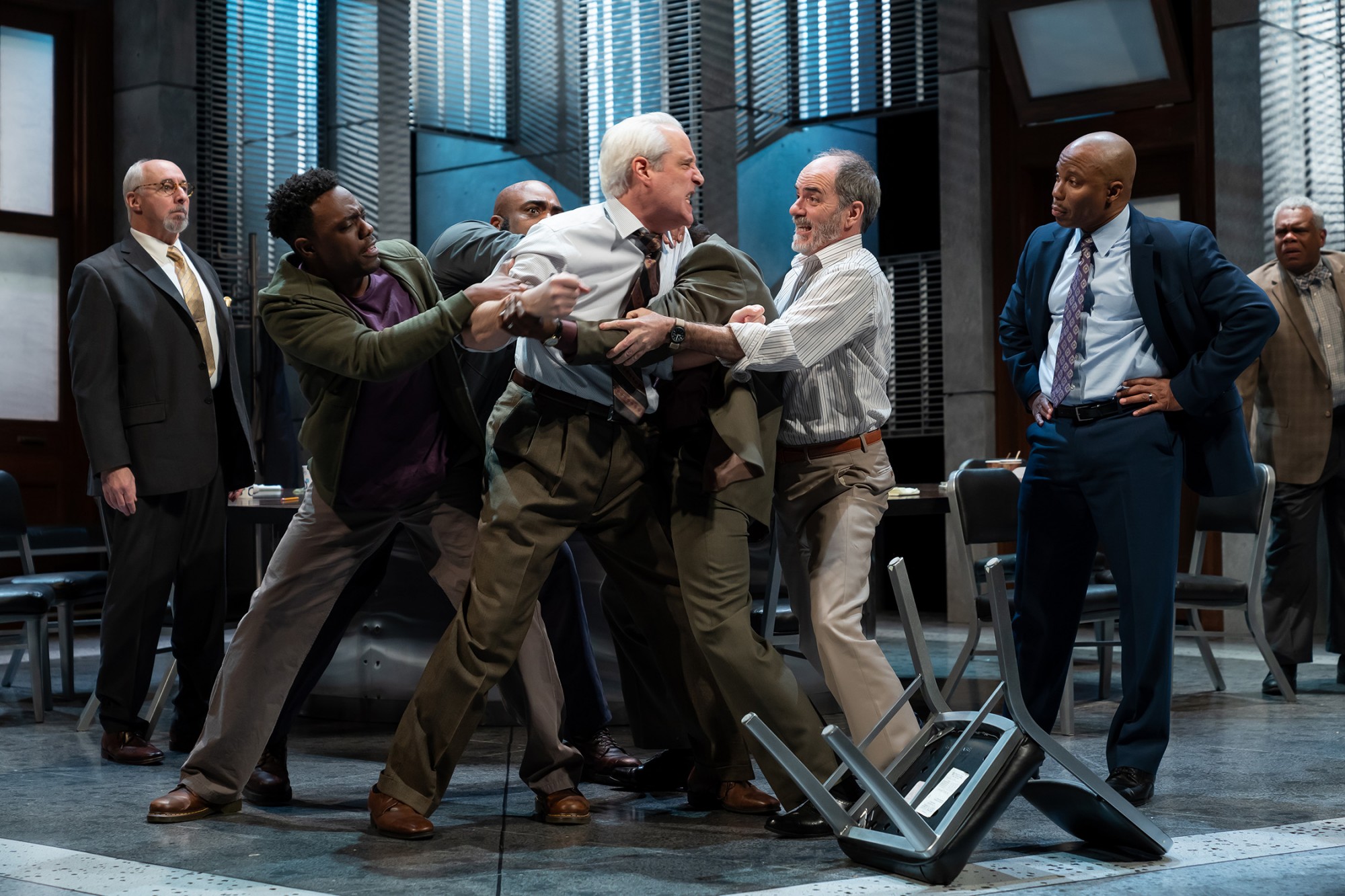 Four men physically restrain an angry man who lunges with fists clenched toward another man in a jury room. Image is from the Ford’s Theatre 2019 production of Twelve Angry Men, directed by Sheldon Epps. Photo by Scott Suchman.