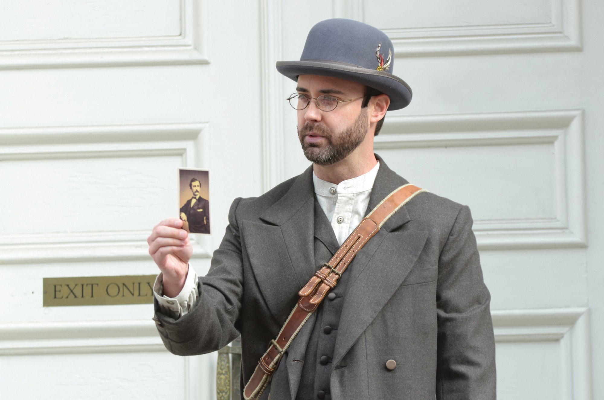 Actor William Diggle, dressed as Detective James McDevitt, holds a photo of assassin John Wilkes Booth as he leads a tour outside of Ford's Theatre.