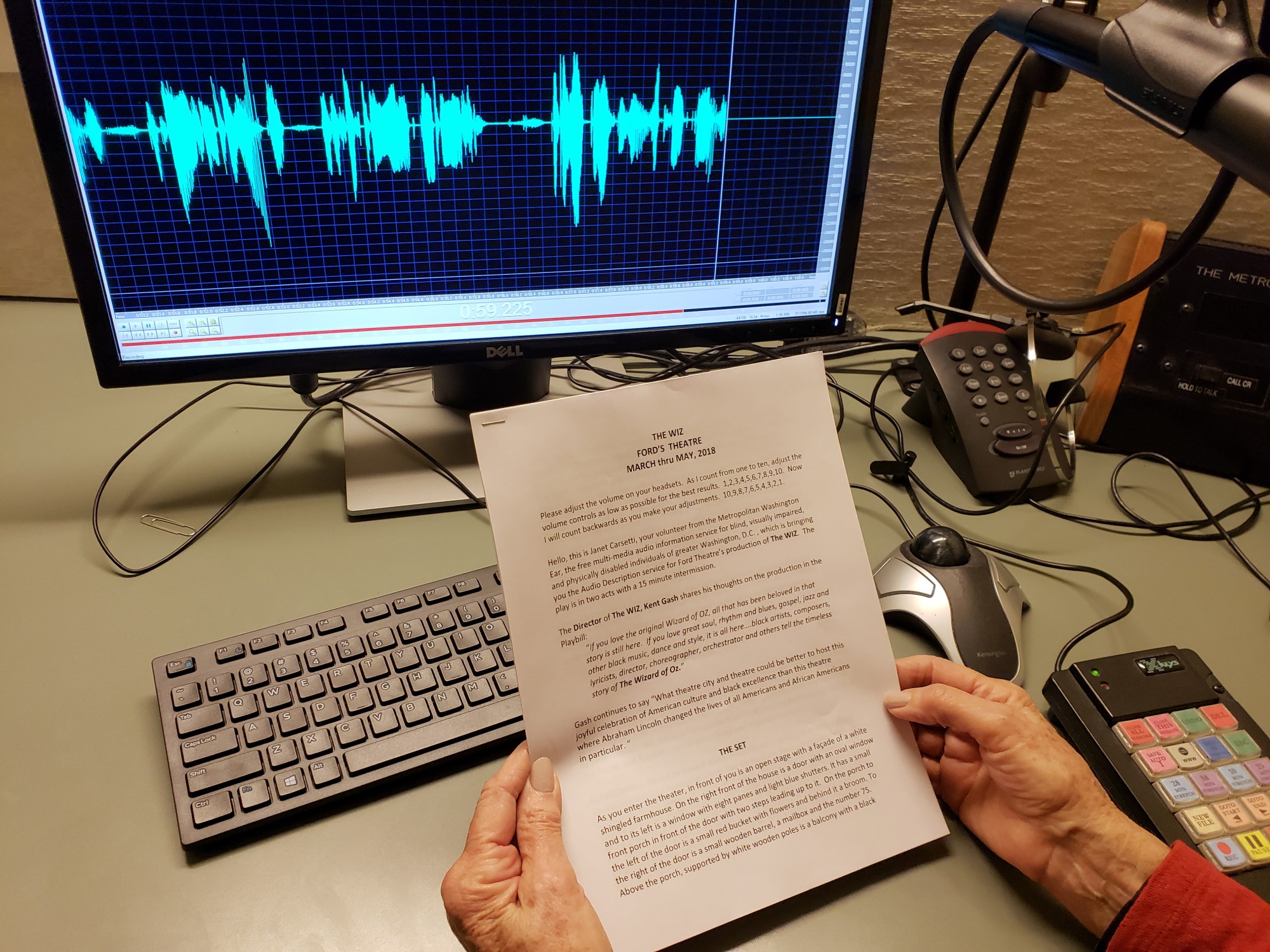 A woman sits behind a microphone and computer in a digital voice recording studio and reads aloud a script of welcome remarks for the Ford’s Theatre stage production of “The Wiz.”