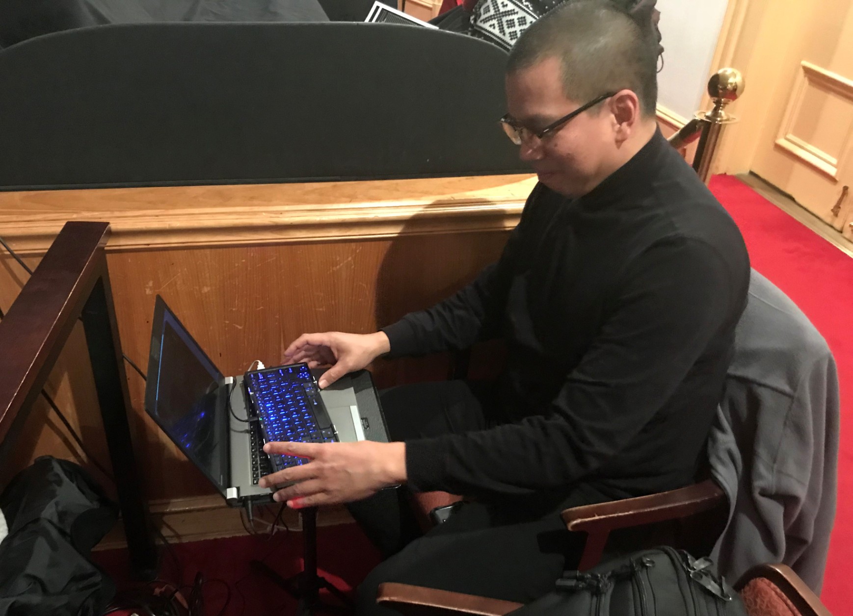 David Chu sits in the back of the orchestra section at Ford's Theatre typing onto a small devices captions which will play during a performance of "Twelve Angry Men"