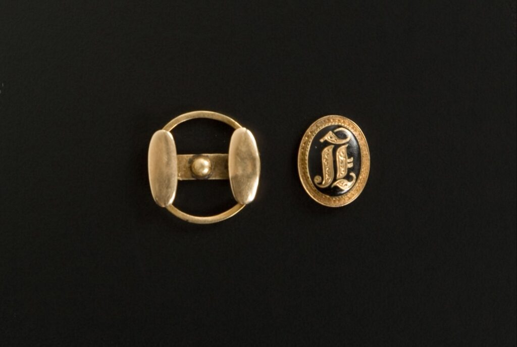 A photograph of a brass cufflink and it's backing.