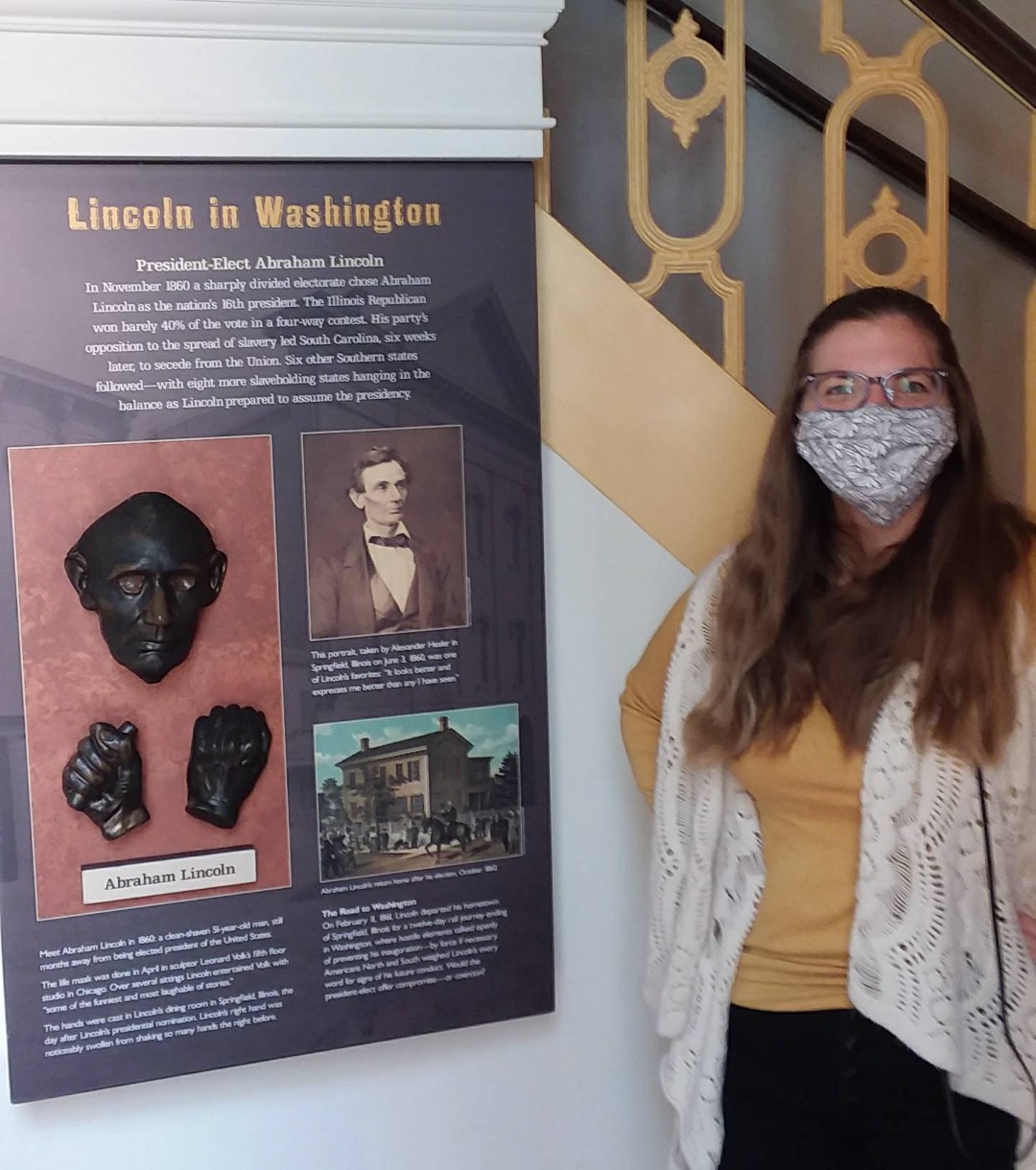 Taryn stands next to a museum panel showing a life mask of Abraham Lincoln.