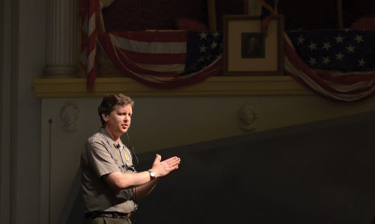 A ranger stands on the stage at Ford's Theatre and gives a talk.