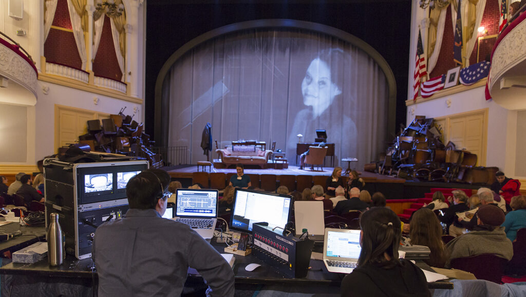 Two stage managers sit behind several laptops and monitors at a tech table before the Invited Dress Rehearsal for The Glass Menagerie at Ford’s Theatre.