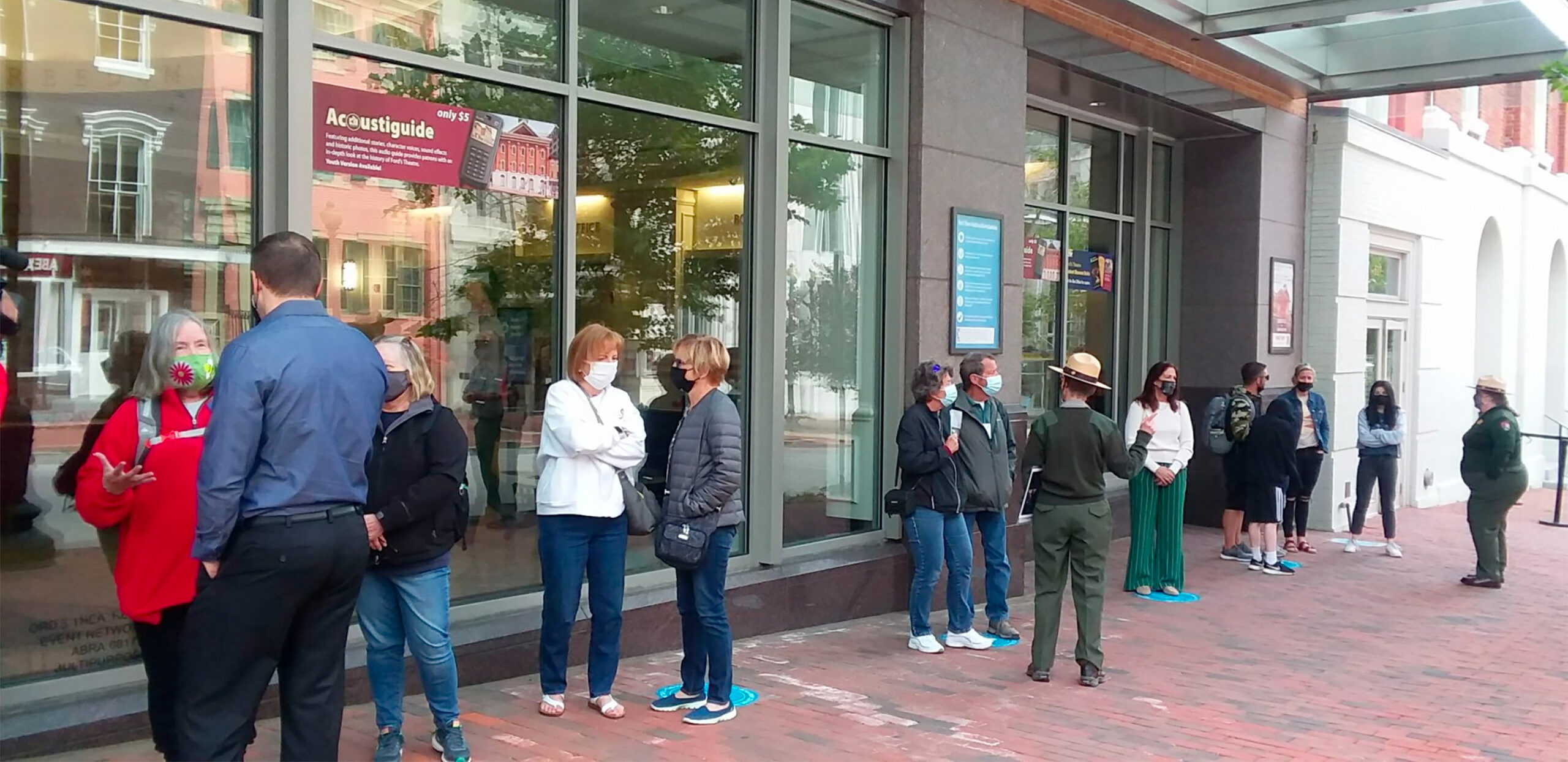 Patrons stand outside of Ford's Theatre wearing face masks and awaiting their timed entry to the lobby.