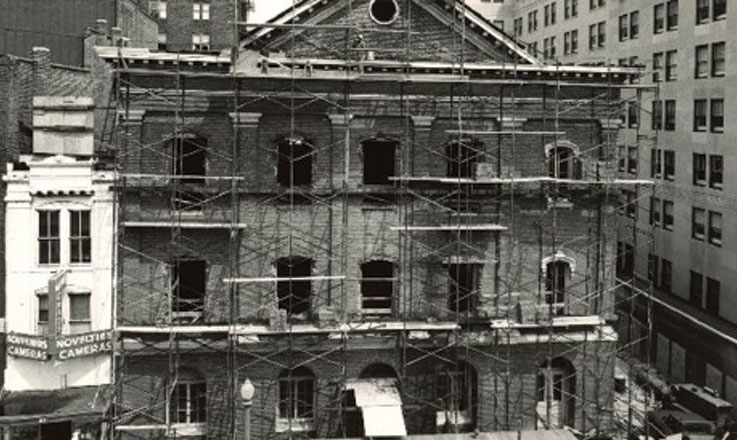 Exterior view of Ford’s Theatre under construction. Scaffolding covers all four stories of the front of the building.