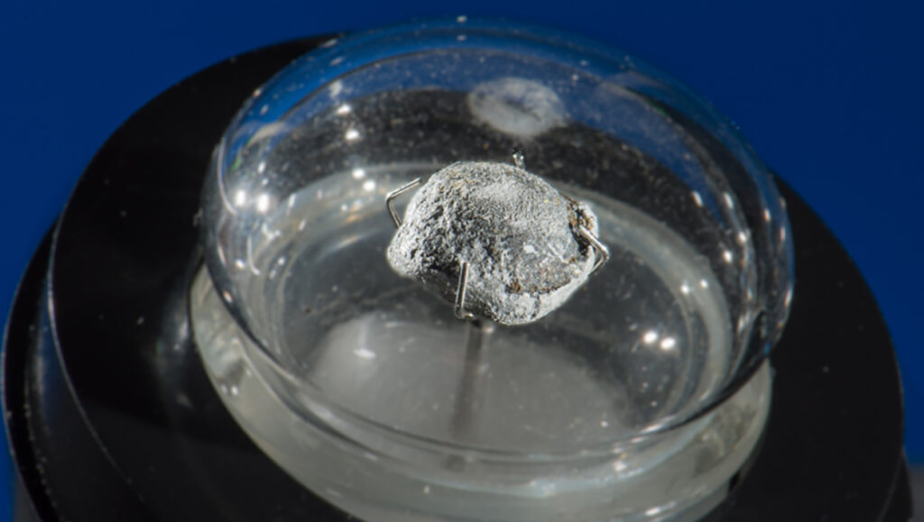 Photograph of a disformed lead bullen contained under glass.