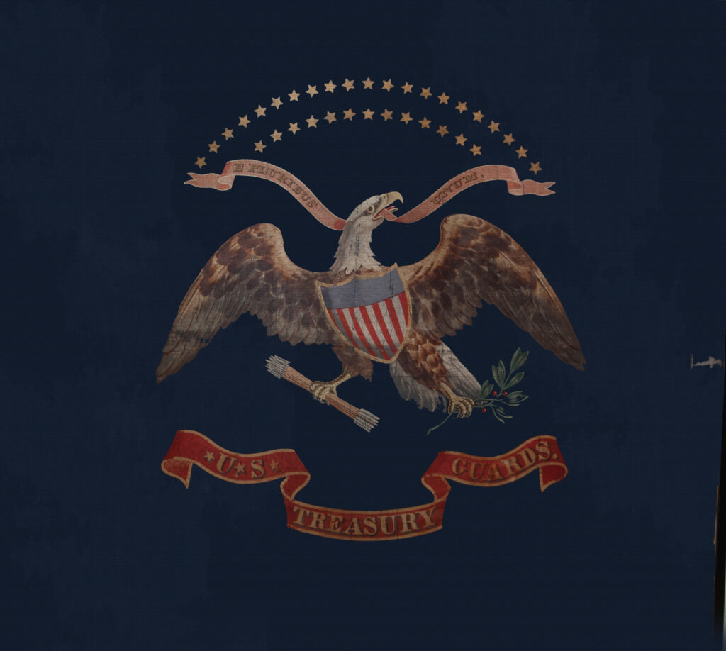 Photograph of a flag with the emblem of an eagle. The eagle is wearing a shield decorated as an American flag, and grasps a bundle of arrows and a spring of a plant in its talons. In its beak is a ribbon that reads "E. Pluribus Unum." A banner beneath the eagle reads U.S. Treasury Guards.