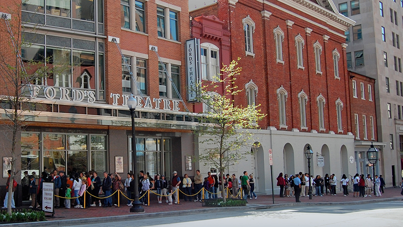 Daytime visitors stand in line on Tenth Street, waiting to enter the lobby of Ford’s Theatre to start their tour or the site.