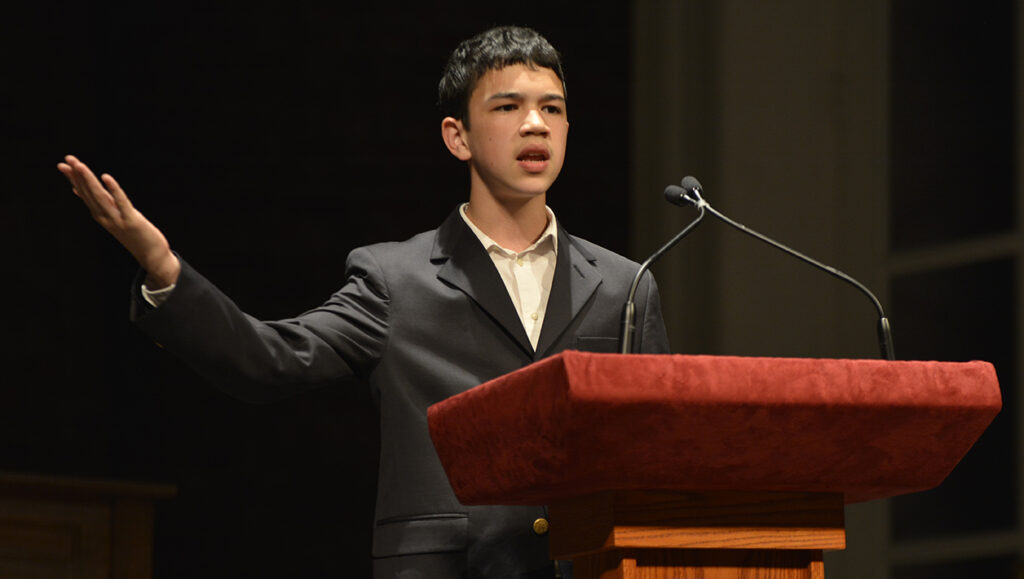 Middle school student performing his speech behind a podium on stage at Ford’s Theatre.