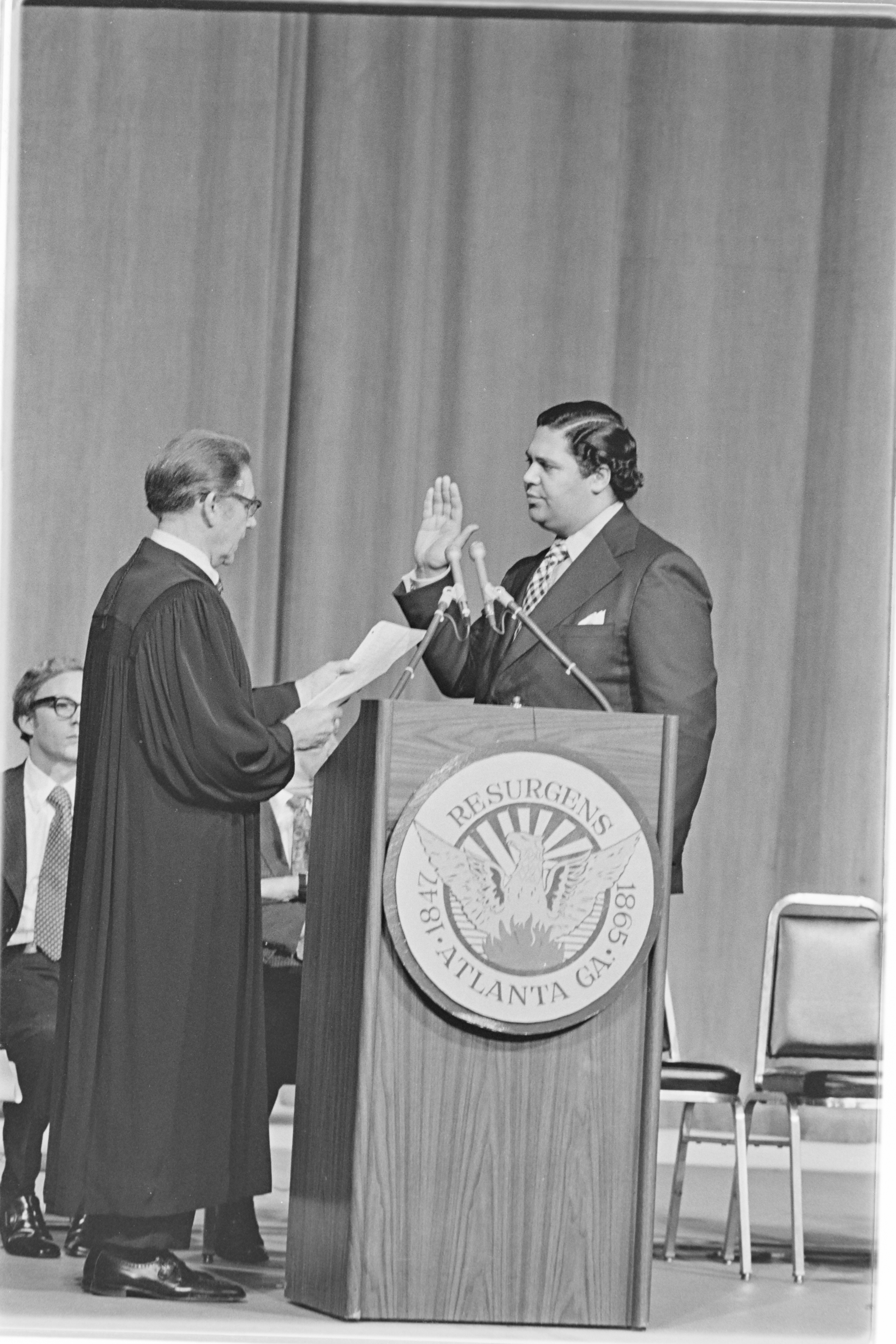 Maynard Jackson, a Black politician, being sworn in as mayor of Atlanta. He stands at a podium, serious and ready.