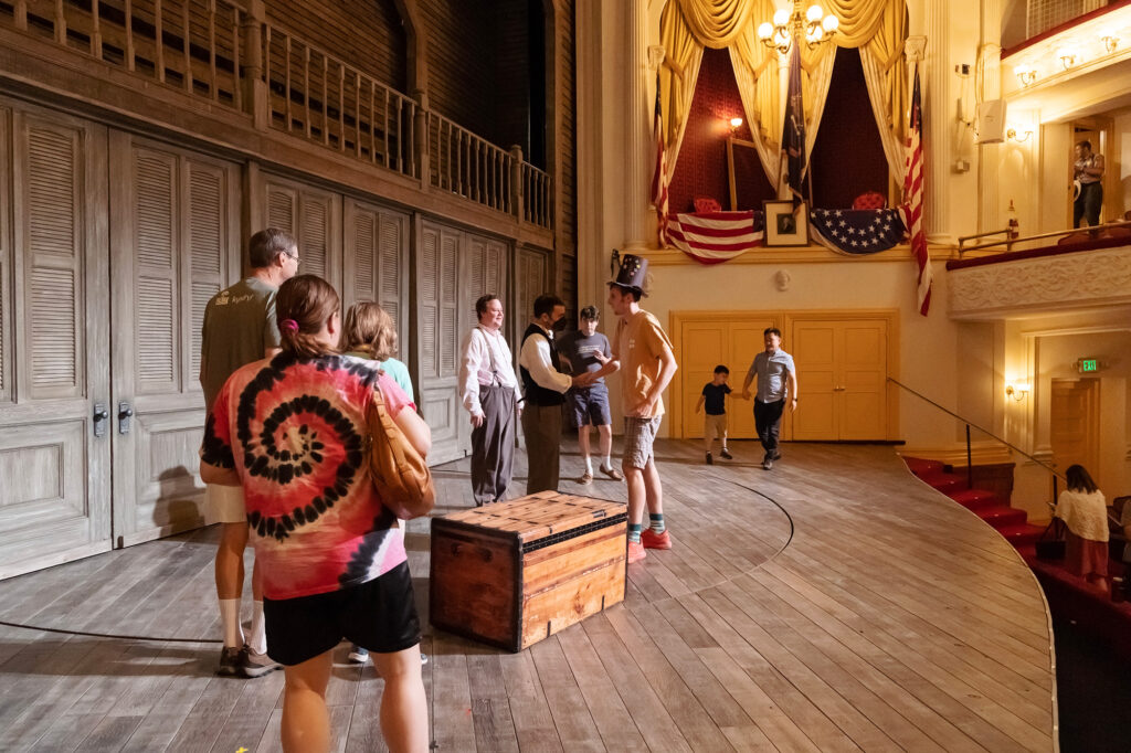 Attendees stand on the Ford’s Theatre stage and meet actors.