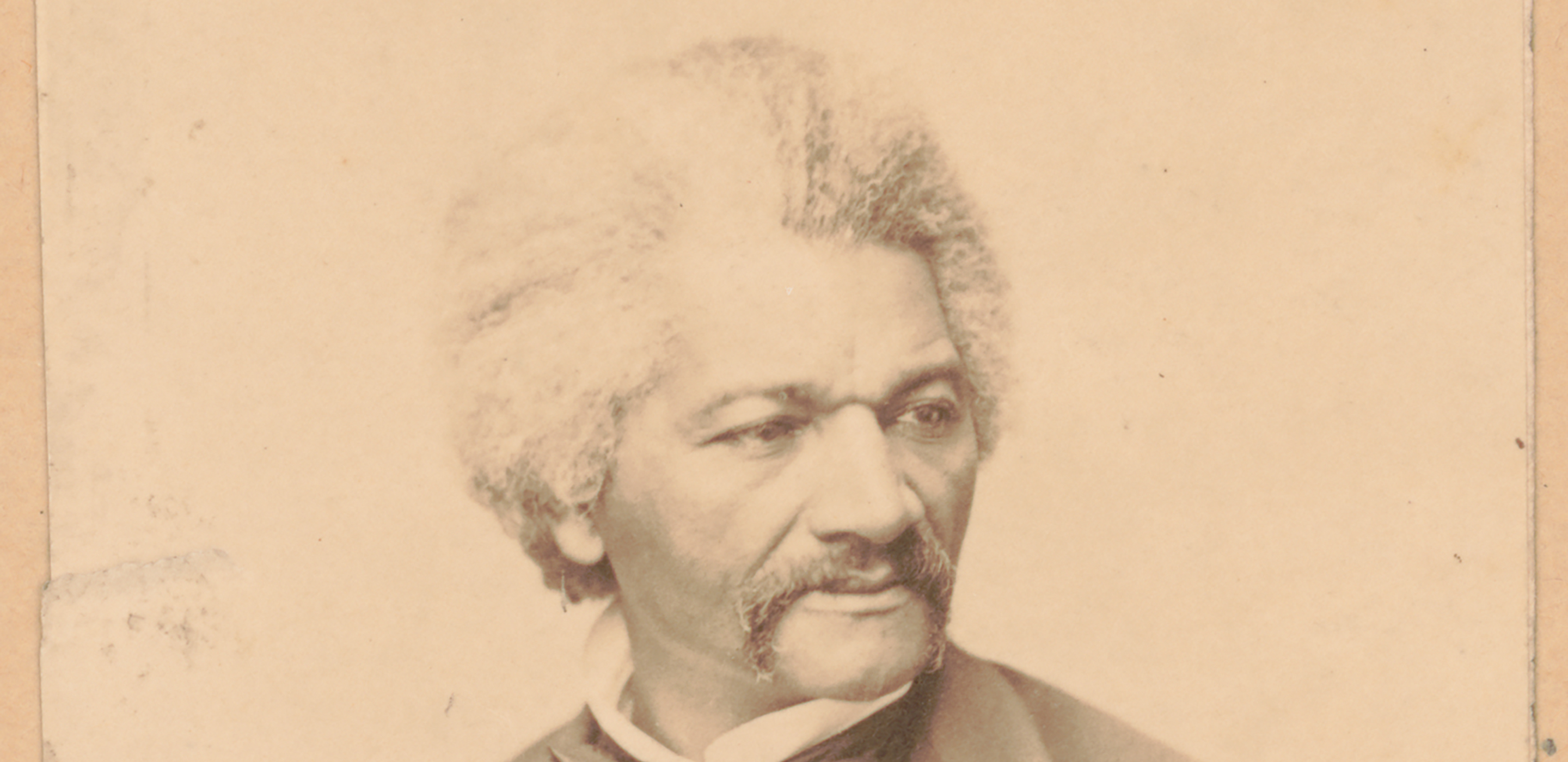 A black and white, 1870 head and shoulders portrait of an African American man with grey hair and a long mustache wearing a black 3-piece suit, white shirt and black bow tie. His gaze is to the right, away from the camera.