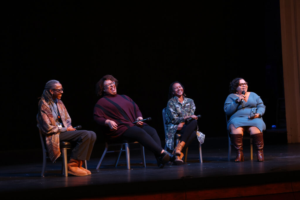 Four Black women sit in chairs on the Ford’s Theatre stage, smiling during a talkback.