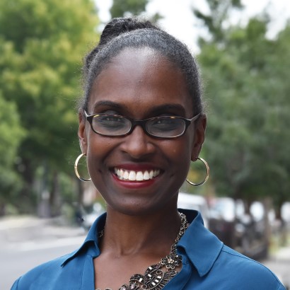 Headshot of a Black woman with glasses wearing a blue shirt.