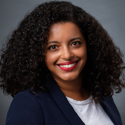 A Black woman wearing a white shirt and blue jacket.