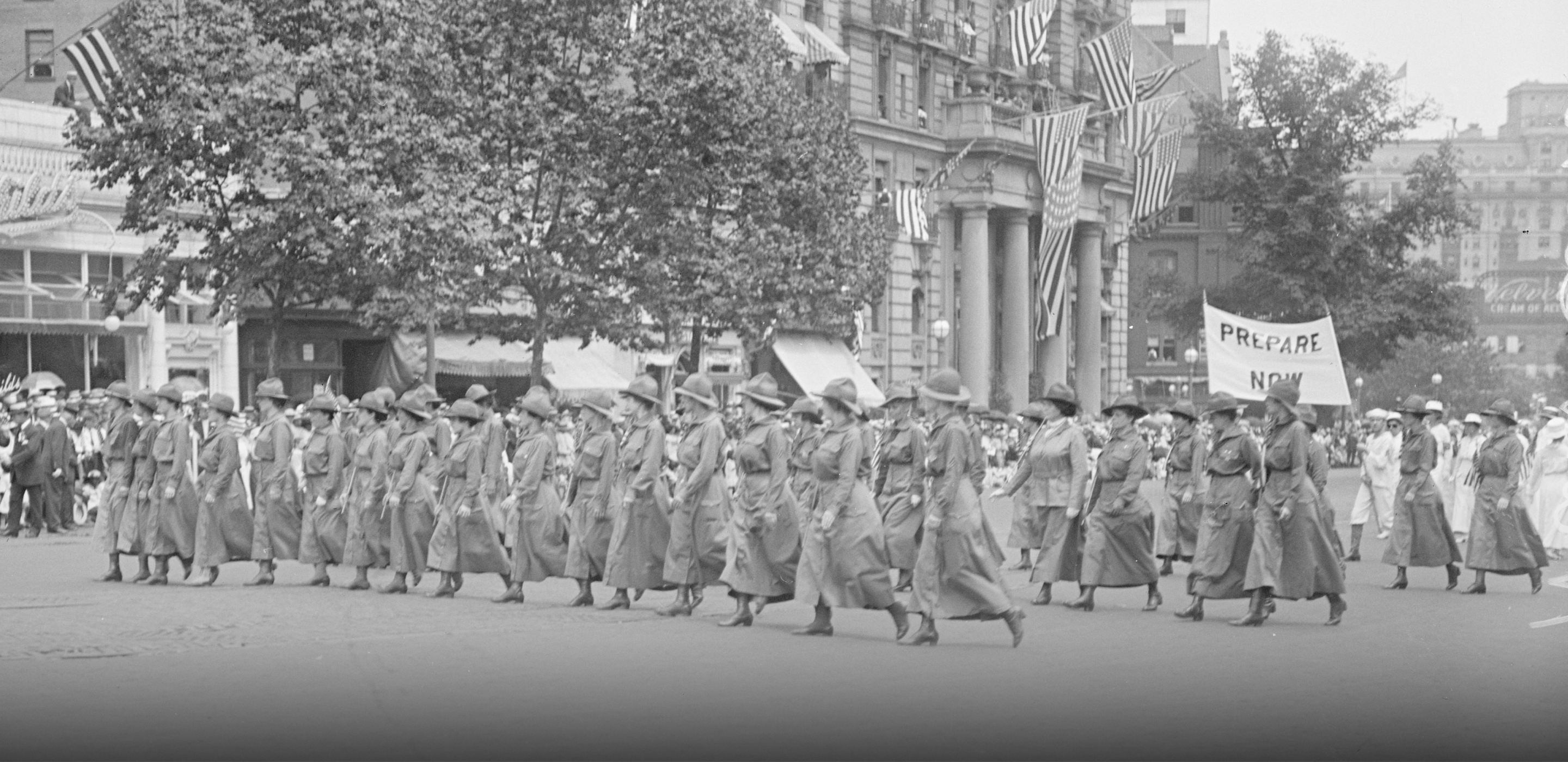 Black and white image of a group of women marching down a wide avenue.