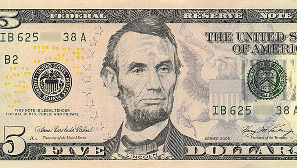 Zoomed in image of a five dollar bill, with Abraham Lincoln's head in the middle.