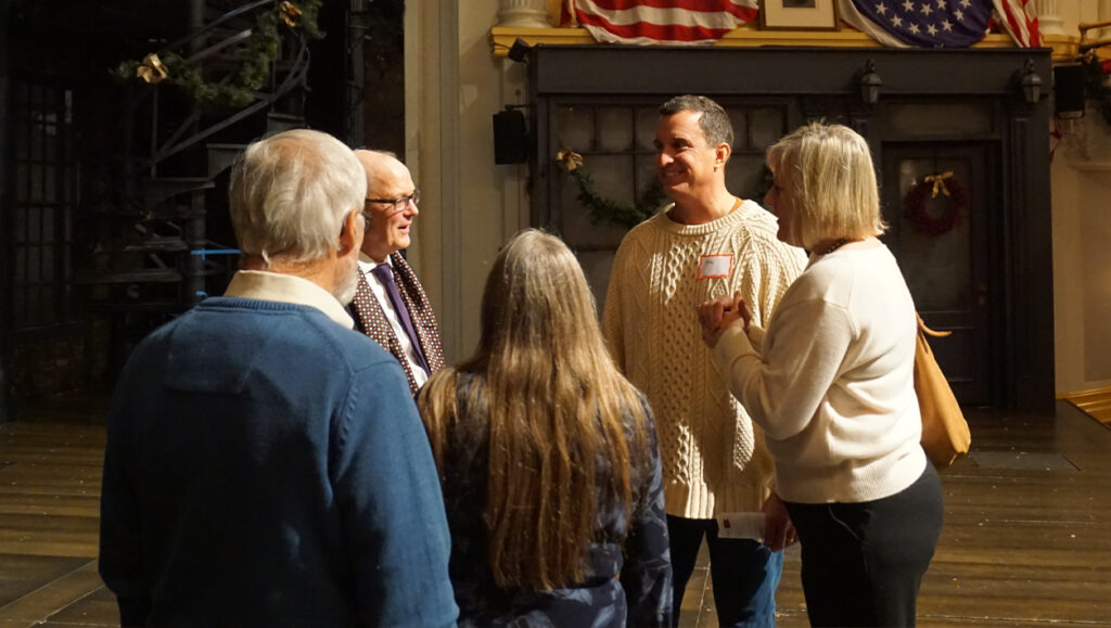 Five people in casual clothing stand on the Ford's Theatre stage and have a discussion.