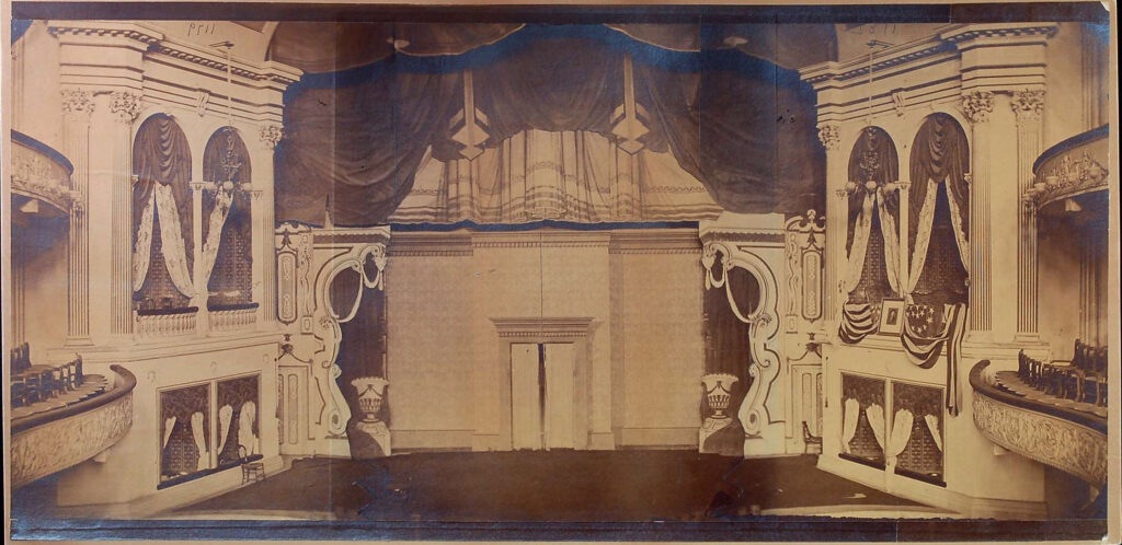 1865 black and white photograph of the empty stage set of Our American Cousin in Ford’s Theatre.