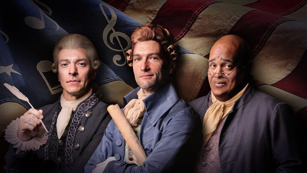 Two white men and a Black man dressed in colonial American clothing standing in front of a waving American flag.