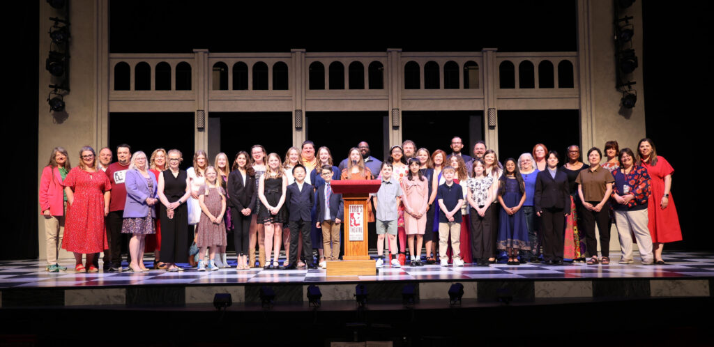 A group of children stand on a stage behind a Ford's Theatre podium.